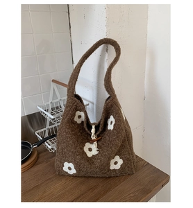 Detail of plush tote bag showing white floral embroidery and wooden toggle button closure