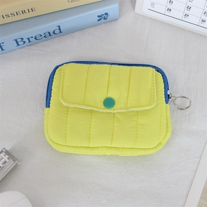 Detailed macro view of yellow quilted mini pouch with blue zipper and green button detail