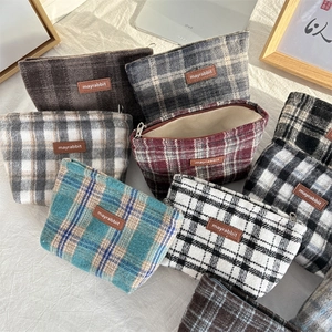Detailweergave van diverse geruite tweed make-up tassen met ritsen en lederen patches