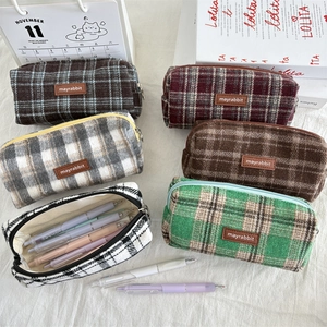 Detailed close-up of colorful wool plaid pencil cases with premium leather logo tags