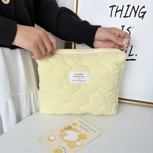 Detail of light yellow quilted makeup bag showing zip closure and soft texture