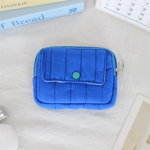 Close-up of bright blue quilted nylon mini pouch with green snap button and metal zip ring