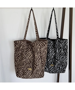 Close-up of zebra print fuzzy tote bags with golden handmade tags in neutral tones