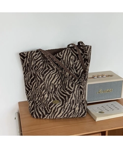 Detail of zebra print tote bag with handmade metal plate on a wooden shelf