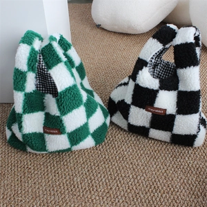 Close-up of checkerboard plush wrist bag showing soft texture and leather brand label