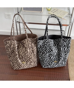 Detail of tiger and zebra print tote bags showing handmade metal logo and soft fuzzy texture