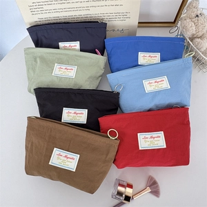Detail view of colorful mini nylon cosmetic bags with circular zipper pulls and woven label