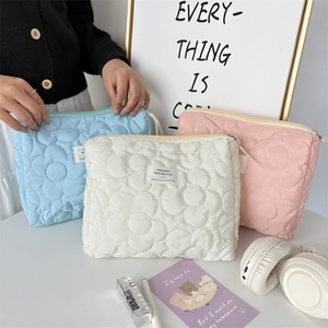 Detailed trio of quilted floral makeup bags in blue, white, and pink on a stylish desk