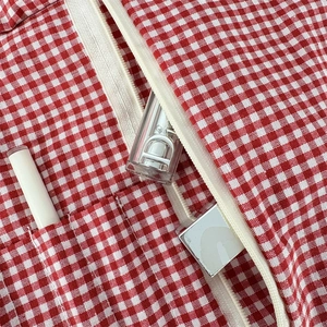 Close-up of red gingham floral makeup bag with cream resin zipper and durable fabric texture