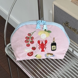 Dettaglio della pochette in nylon rosa con ricami di frutta e zip blu a forma di orso
