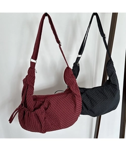 Detail view of burgundy and black checkered canvas crescent bags with wide straps