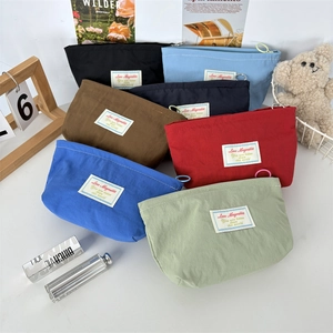 Flat lay of colorful nylon makeup bags in macaron shades with zipper closure and brand label