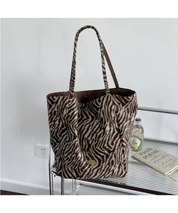 Detail of zebra print faux fur tote bag with golden plaque and long shoulder straps