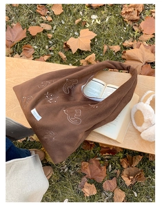Close-up of bird and floral embroidery on a dark brown large capacity tote bag