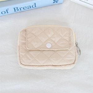 Close-up of quilted beige mini pouch with silver ring zipper and white snap button detail