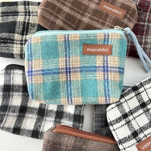 Macro detail of checkered wool fabric pouches with smooth zippers and leather labels