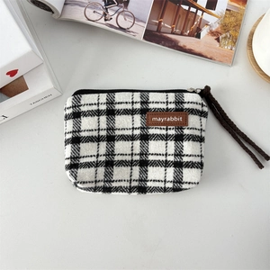 Close-up of black and white checkered canvas pouch with leather tag and zipper