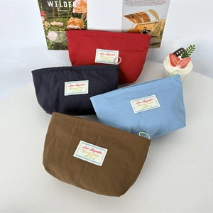 Set of four portable macaron-colored mini cosmetic bags on a white table