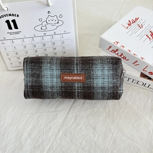 Close-up of vintage plaid wool pencil case with brown leather tag and zipper closure