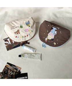 Dettaglio di pochette per il trucco in tela a semicerchio con ricami a cartoni animati