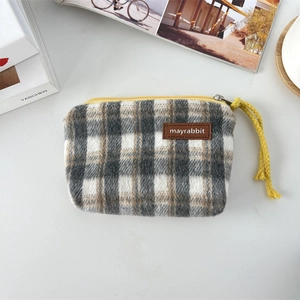 Detail of plaid coin purse with yellow zipper and brown leather label on canvas fabric
