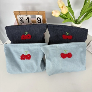Détail macro du tissu denim de qualité avec broderie cerise 3D et fermeture éclair