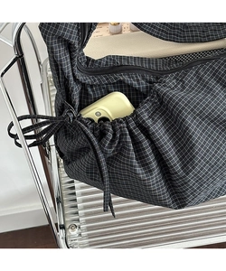 Detail of canvas bag side pocket holding a phone, featuring black and white plaid pattern
