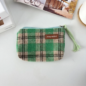 Detail shot of a green plaid canvas coin purse with a textured fabric and woven zip puller