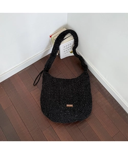 Detail der schwarzen Plüsch-Hobo-Tasche mit Leder-Logo-Patch auf strukturiertem Stoff