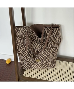 Detailed close-up of fuzzy zebra print tote bag featuring a golden handmade metal plaque