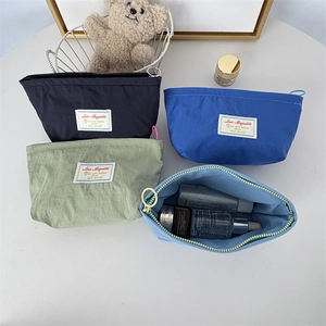 Set of four pastel mini nylon makeup bags with zippers shown on a flat lay background