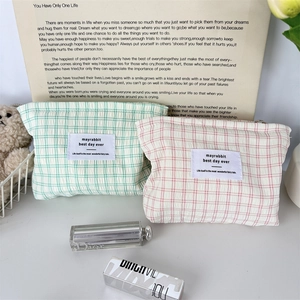 Détail de trousses à maquillage en coton à carreaux avec fermetures éclair et étiquettes