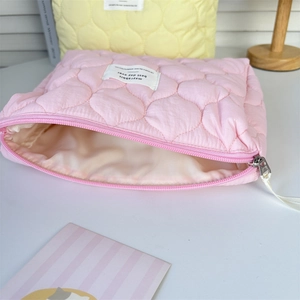 Detail of pink quilted cosmetic bag featuring heart pattern and silver metal zipper closure