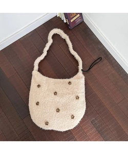 Detailansicht der beigen Plüschtasche mit braunen Blumen-Patches auf Holzboden