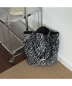 Detailed close-up of zebra print tote bag featuring a gold handmade metal plaque