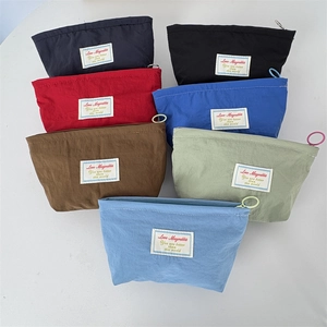 Detailed view of colorful mini nylon cosmetic bags with circular zipper rings and labels