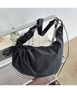 Detail of checkered canvas hobo bag with pleated texture on a modern metal shelf