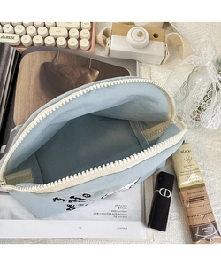 Vista dettagliata della borsa in nylon azzurro con cerniera bianca e scritte ricamate