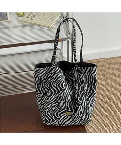 Detailed close-up of zebra pattern tote bag with gold metal handmade logo plate