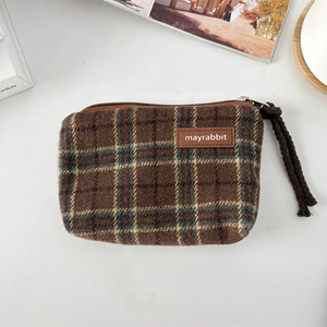 Close-up of vintage plaid canvas pouch with brown leather logo and woven zipper pull