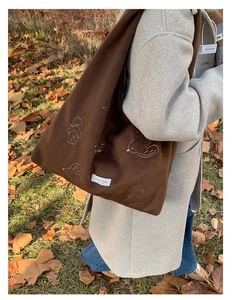 Close-up of bird embroidery on a brown wool hobo tote bag with YOURJOLLYHOUSE label