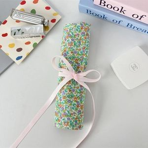 Floral makeup brush roll bag detail with pink ribbon bow on green cotton fabric