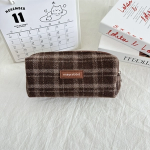 Detail of vintage brown plaid wool pencil case with premium leather brand label