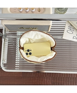 Macro view of compact yellow nylon makeup bag showing spacious interior with a phone inside