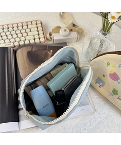 Vista dall'alto della borsa da trucco blu ricamata che mostra lo spazio interno per i cosmetici