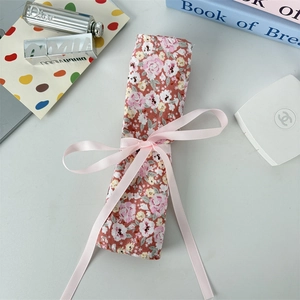 Macro view of floral fabric makeup roll bag with pink silk ribbon bow closure