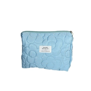 Light blue floral quilted makeup bag with zipper closure and logo label on white background