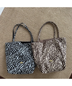 Close-up of zebra pattern plush fabric texture and handmade metal tag on large tote bags