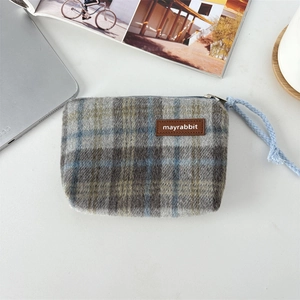 Macro detail of plaid tweed fabric texture and leather logo patch on mini coin purse