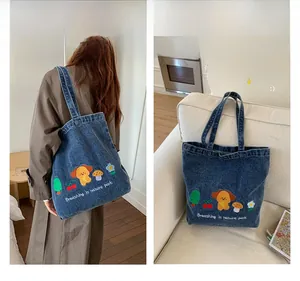 Detail of blue denim tote bag with colorful dog and mushroom embroidery and white text
